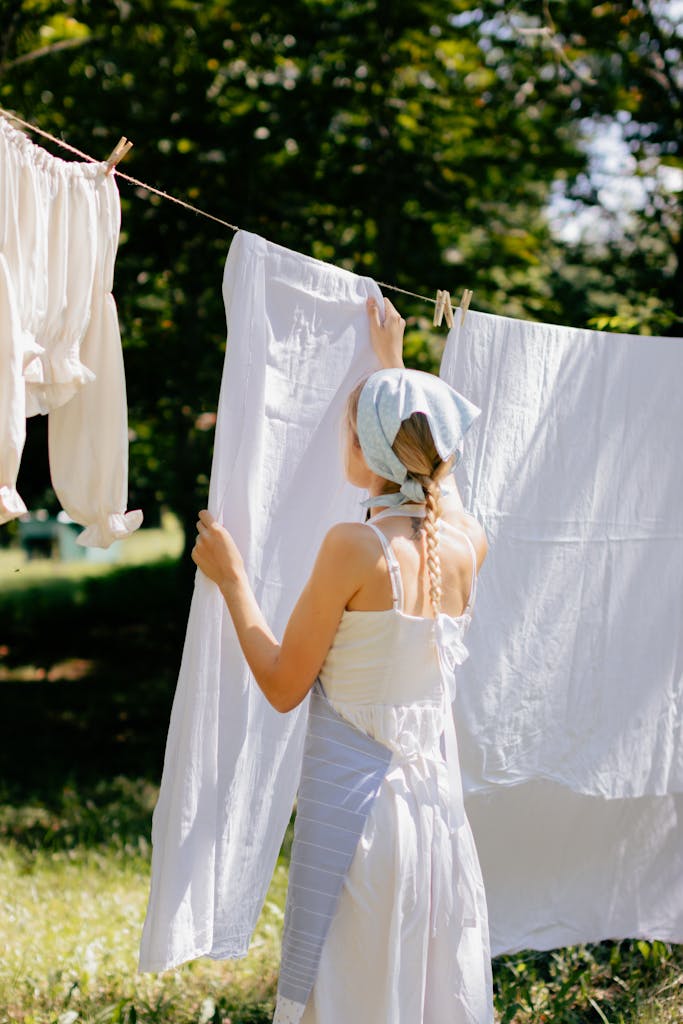 Young woman hangs clothes on a line, enjoying a sunny day in the garden.