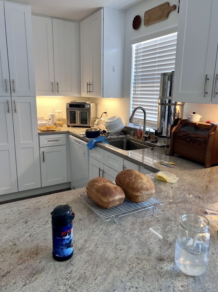 A lived in kitchen with freshly baked bread , clean stacked dishes, showing a peaceful moment in a homemaker's daily routine.