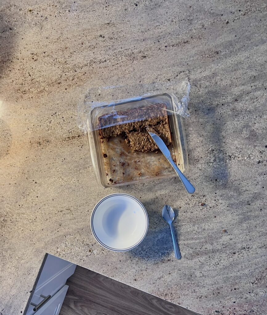 Homemade muffin cake served in a pan already half eaten, showing a simple from-scratch family breakfast in a busy home kitchen.